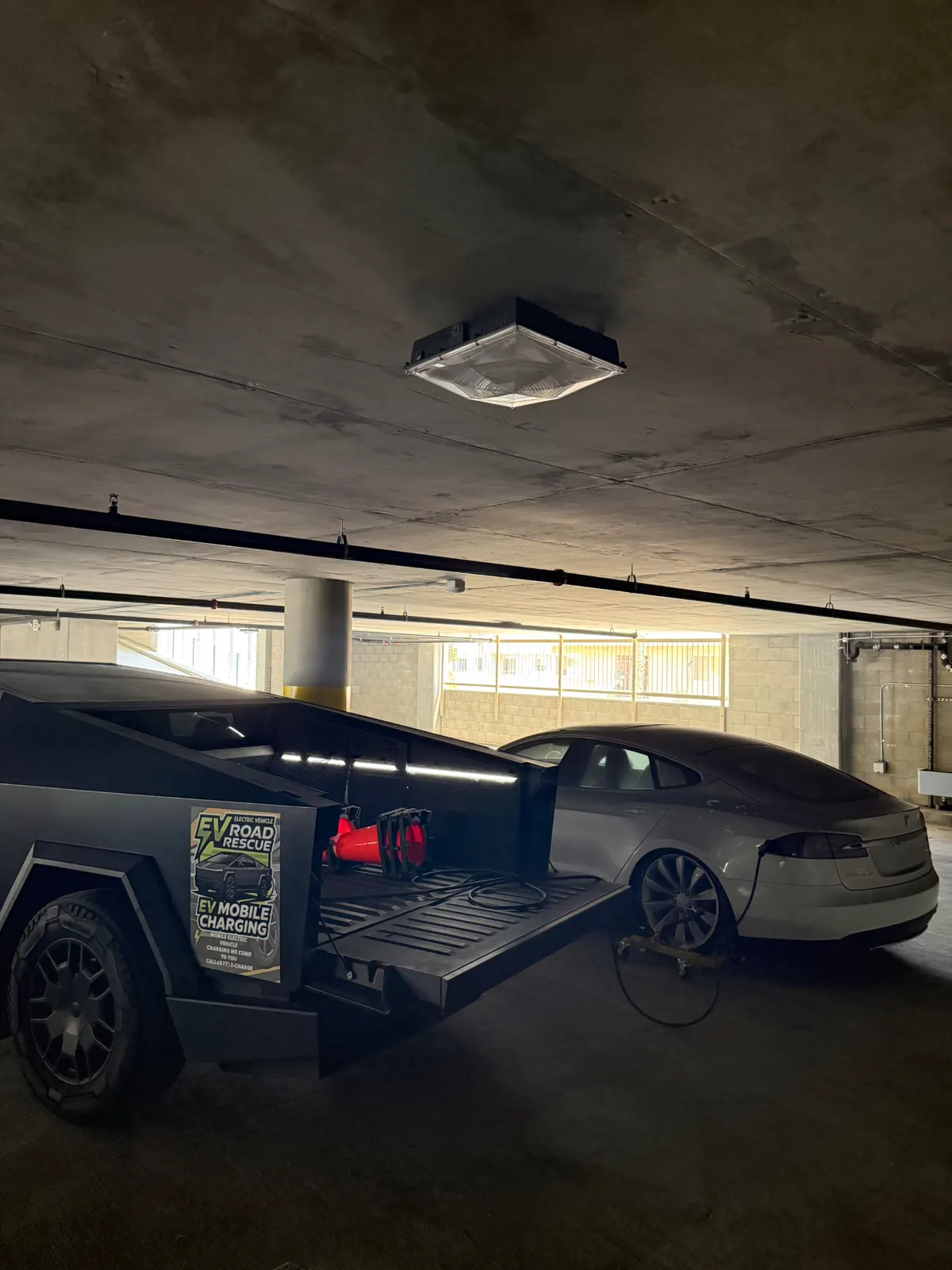 CyberCharge Cybertruck charging a Tesla in a parking garage